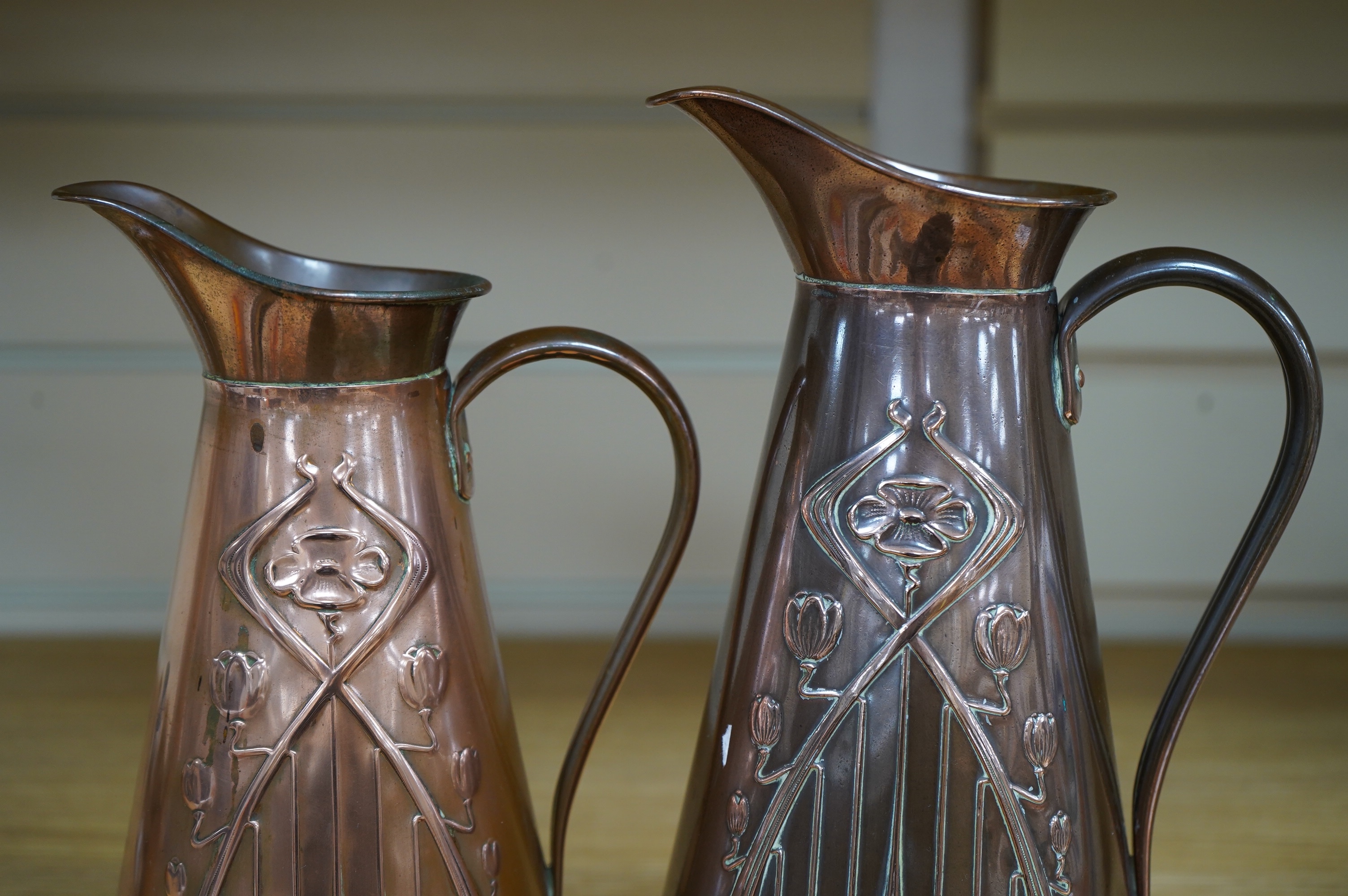 Two Joseph Sankey Art Nouveau embossed copper jugs, tallest 23cm. Condition- fair to good